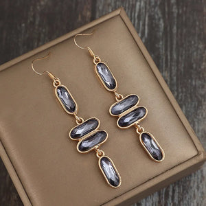 Gold geometric stone cascade earrings with faceted grey stones.