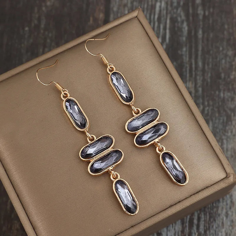 Gold geometric stone cascade earrings with faceted grey stones.