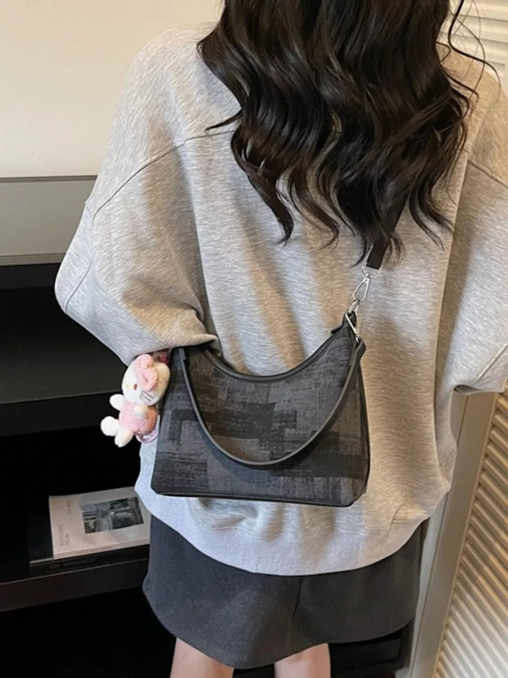 Black pu leather shoulder bag with abstract pattern and plush charm.