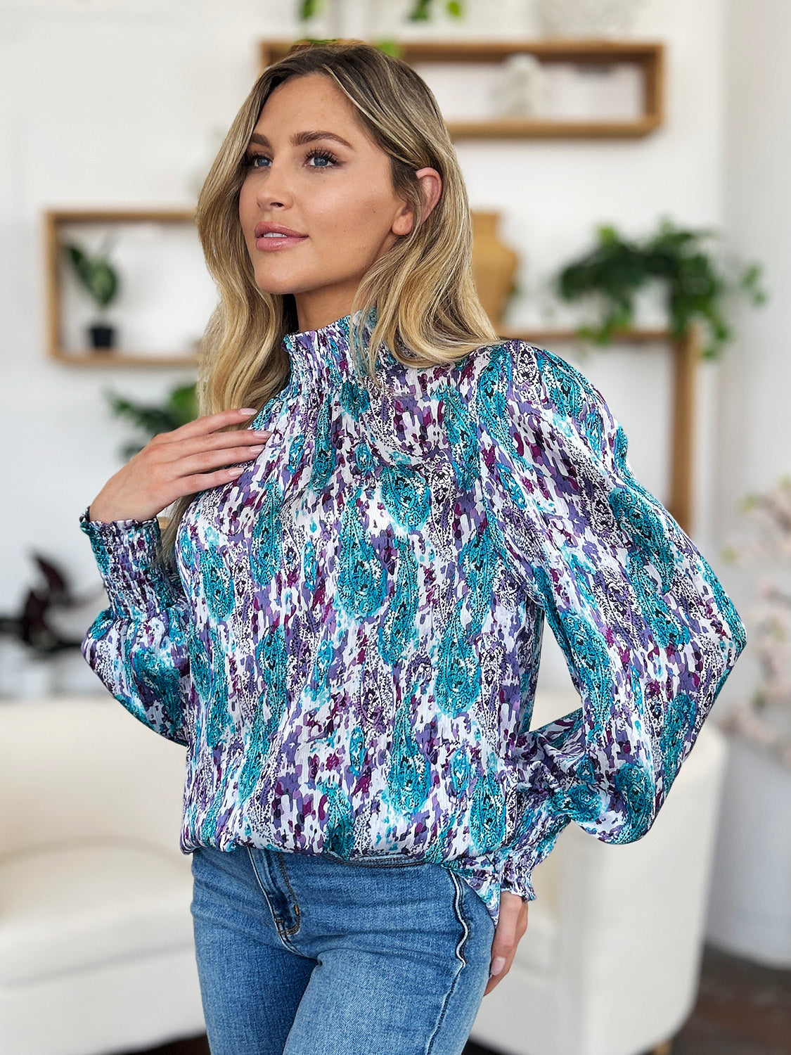 High neck abstract print blouse with smocked cuffs and neckline in blue and red-violet.