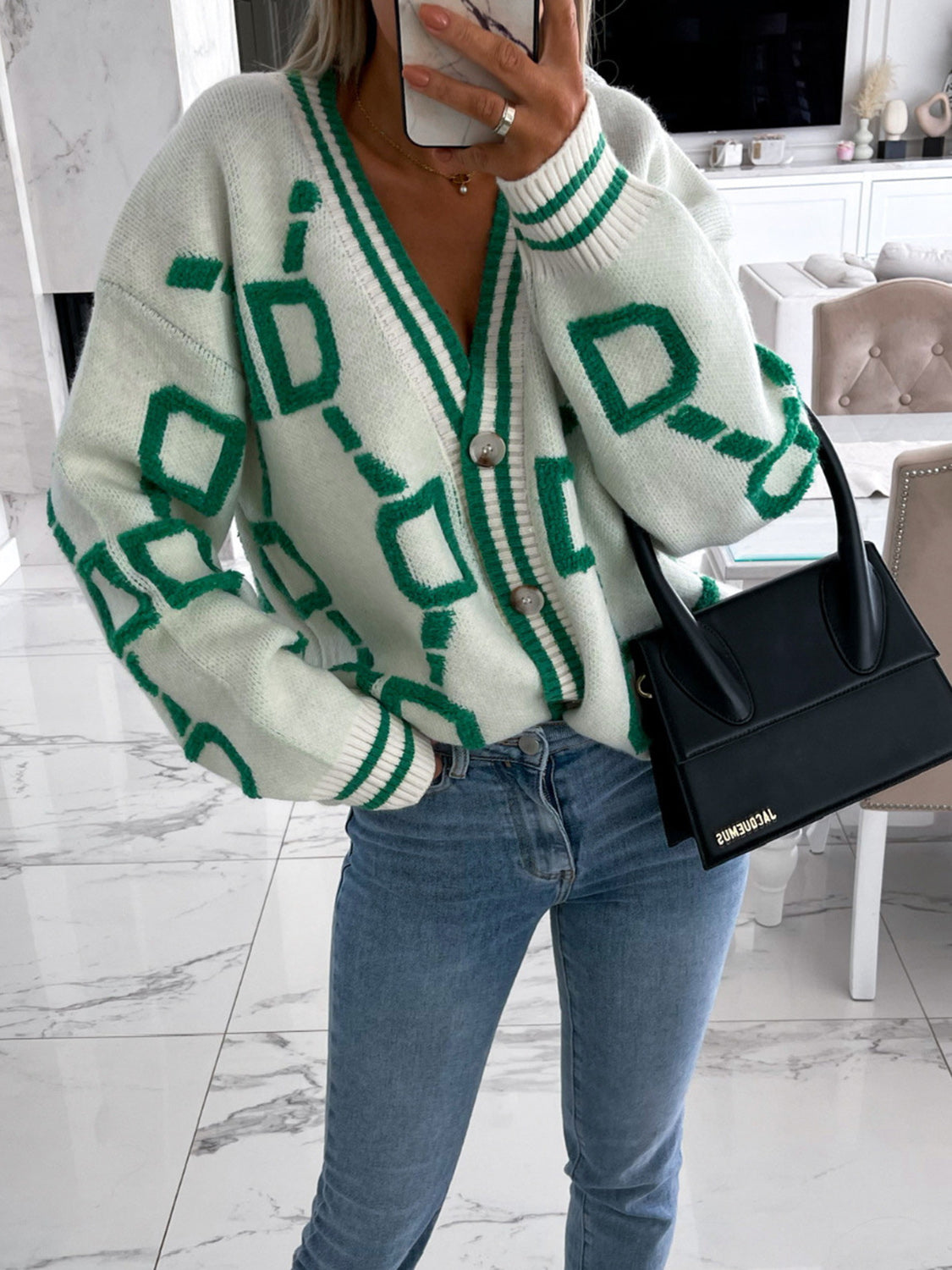 White acrylic cardigan with green geometric chain pattern, V-neck, button front, and striped cuffs.