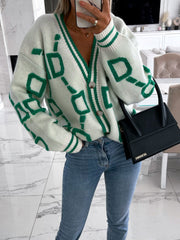 White acrylic cardigan with green geometric chain pattern, V-neck, button front, and striped cuffs.