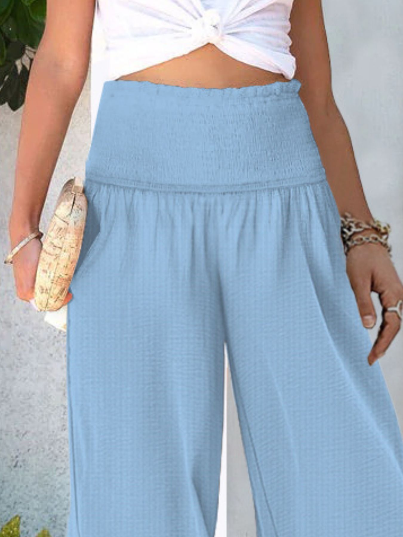 Sky blue smocked waist wide-leg pants with textured fabric and a relaxed fit.