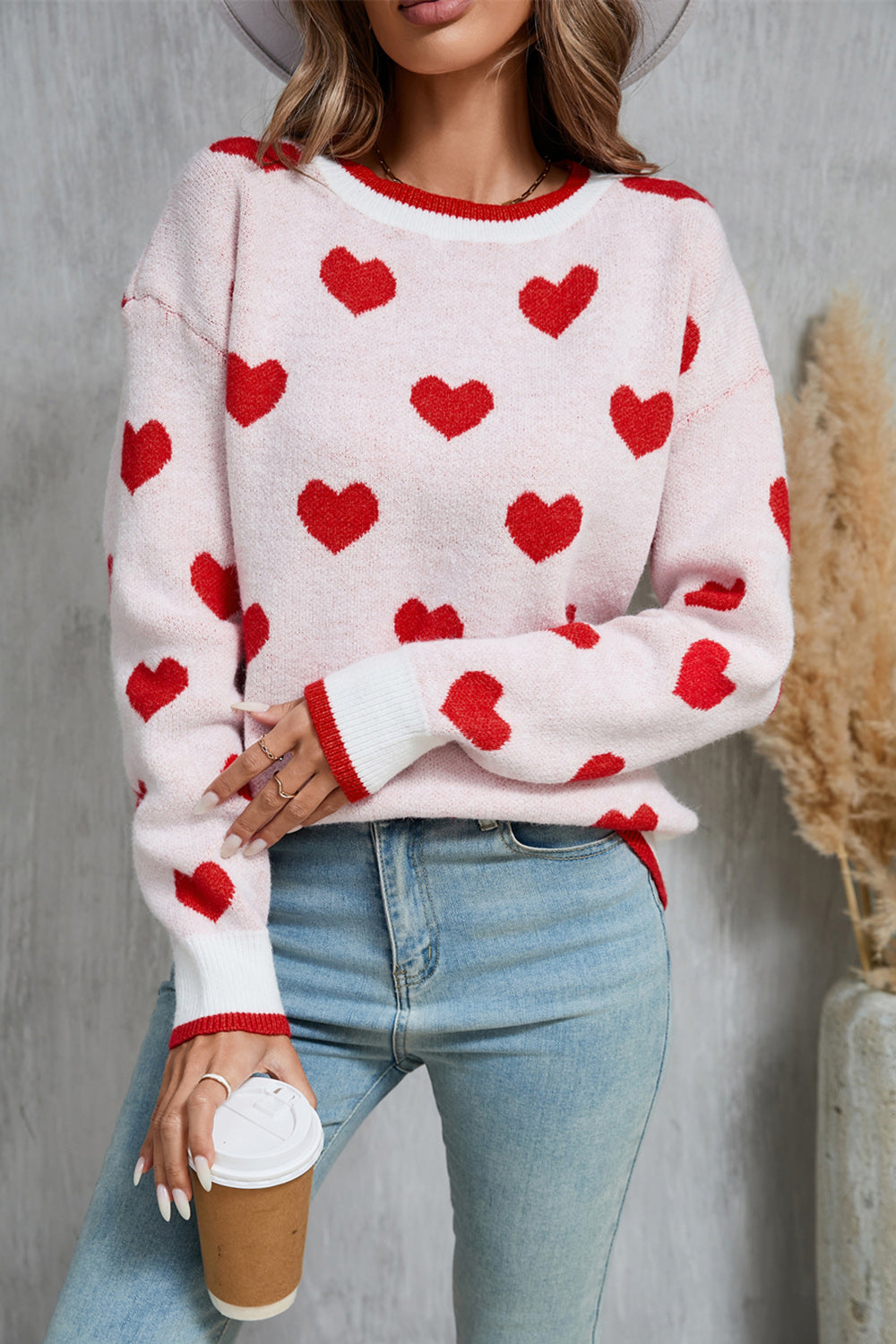 Pink crewneck sweater with red hearts pattern, ribbed cuffs and neckline.