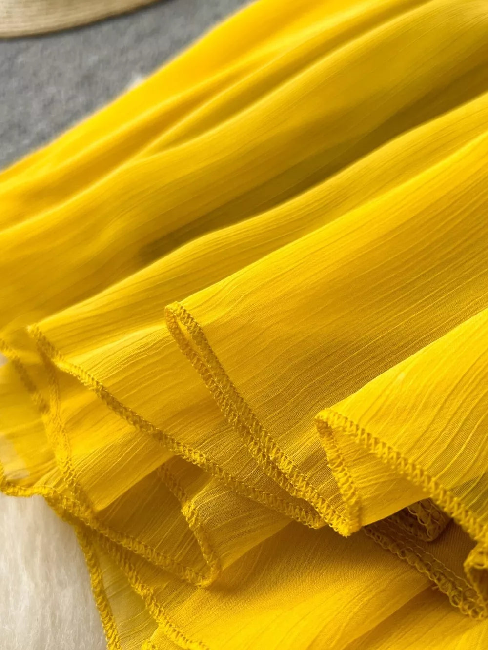 Yellow chiffon dress with ruffled layers and textured fabric detail.