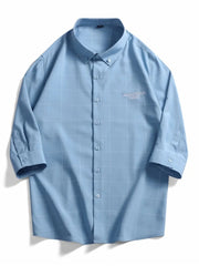 Blue oversized plaid button-down shirt with embroidered text detail.