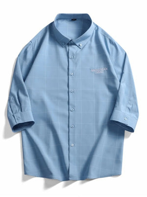 Blue oversized plaid button-down shirt with embroidered text detail.