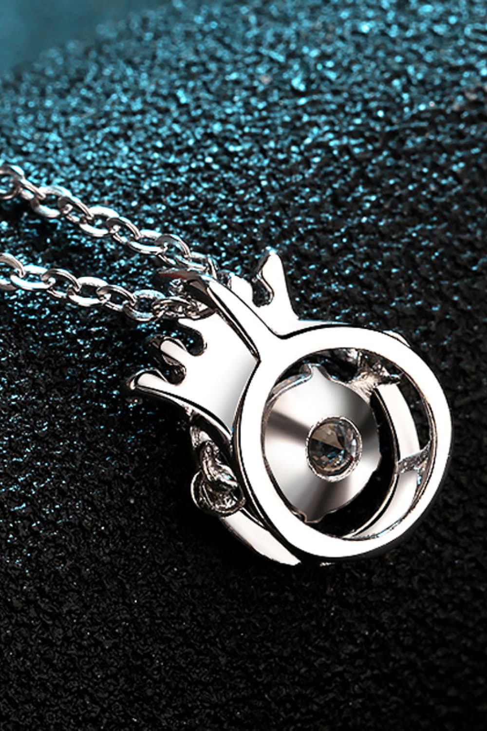 Silver pendant necklace with a crown design and a central crystal detail.