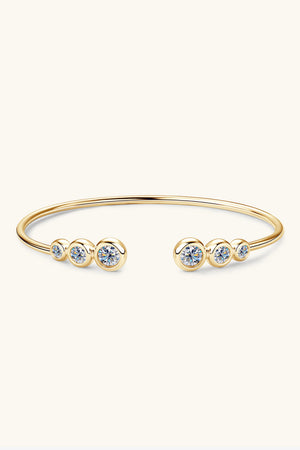 Gold open-ended cuff bracelet with five bezel-set moissanite stones.