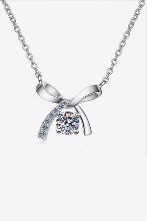 Silver bow-tie diamond pendant necklace with a central round-cut diamond and accent stones.