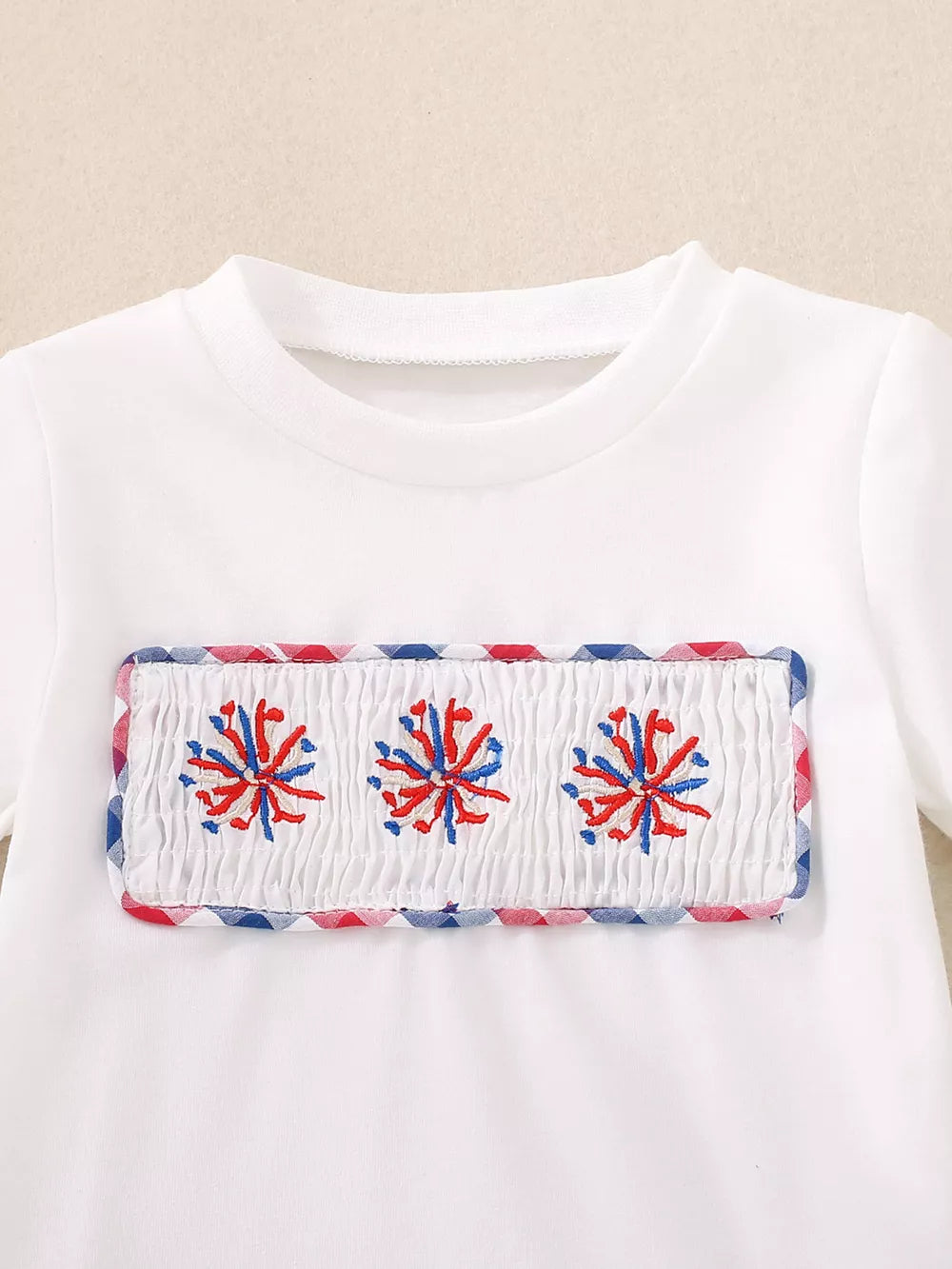 White cotton tee with smocked panel and red, white, blue fireworks embroidery.