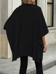 Black knit asymmetrical zip-neck poncho with short sleeves and side slits.