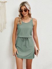 Sage green eyelet crossover strap mini dress with drawstring waist.