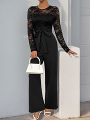 Black lace bodice wide-leg jumpsuit with tie waist and long sleeves.