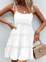White dotted swiss tiered mini dress with tie straps and ruffled tiers.