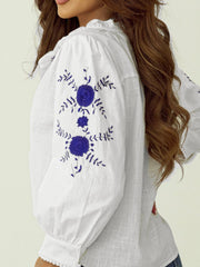 White linen blouse with blue floral embroidery and scalloped trim detail