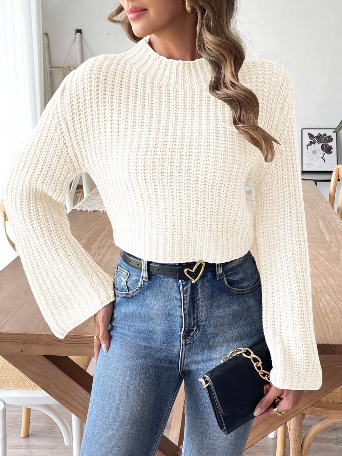 White ribbed crop sweater with bell sleeves and mock neck, styled with jeans.