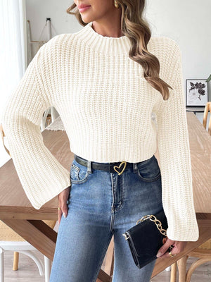 White ribbed crop sweater with bell sleeves and mock neck, styled with jeans.