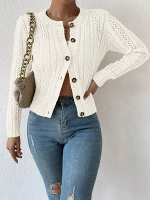 White cable-knit button-front cardigan with round neckline and brown buttons.