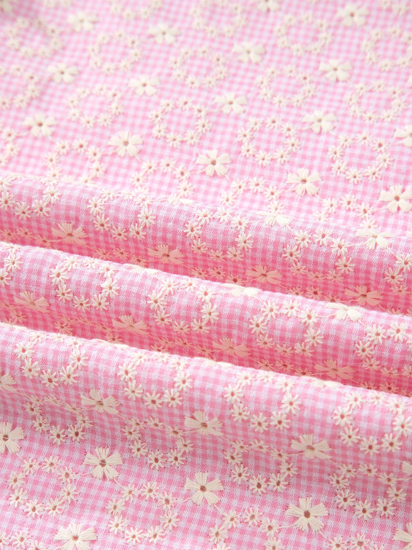 Pink gingham cotton blouse with eyelet floral embroidery and flutter sleeves.