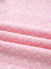 Pink gingham cotton blouse with eyelet floral embroidery and flutter sleeves.