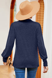 Dark blue buttoned blouse with lantern sleeves and button detail on cuffs.