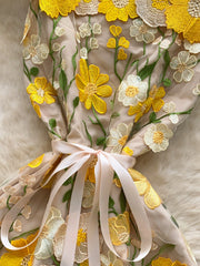 Embroidered floral mini dress in beige with yellow and white flowers, featuring a bow detail.