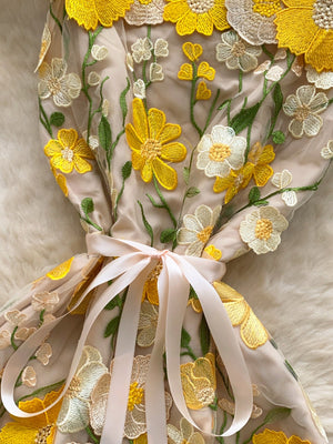 Embroidered floral mini dress in beige with yellow and white flowers, featuring a bow detail.