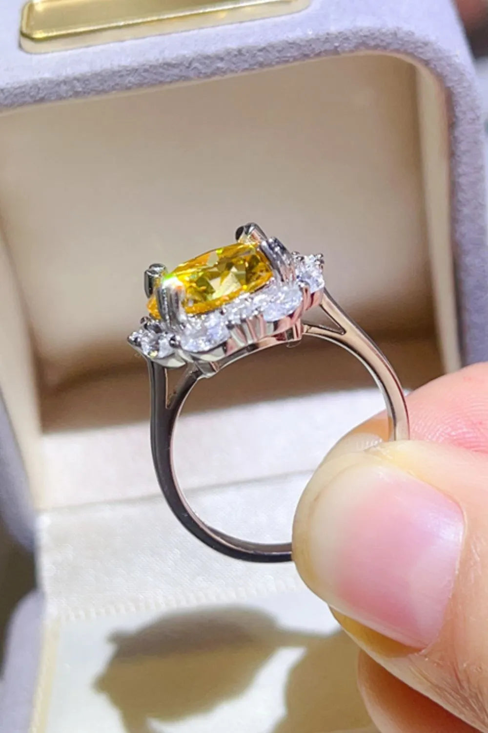 Yellow gemstone halo ring with clear accent stones on a silver band.