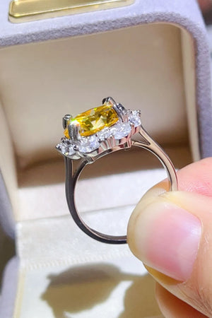 Yellow gemstone halo ring with clear accent stones on a silver band.