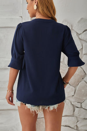 Dark blue puffed sleeve blouse with flared cuffs and a V-neck.