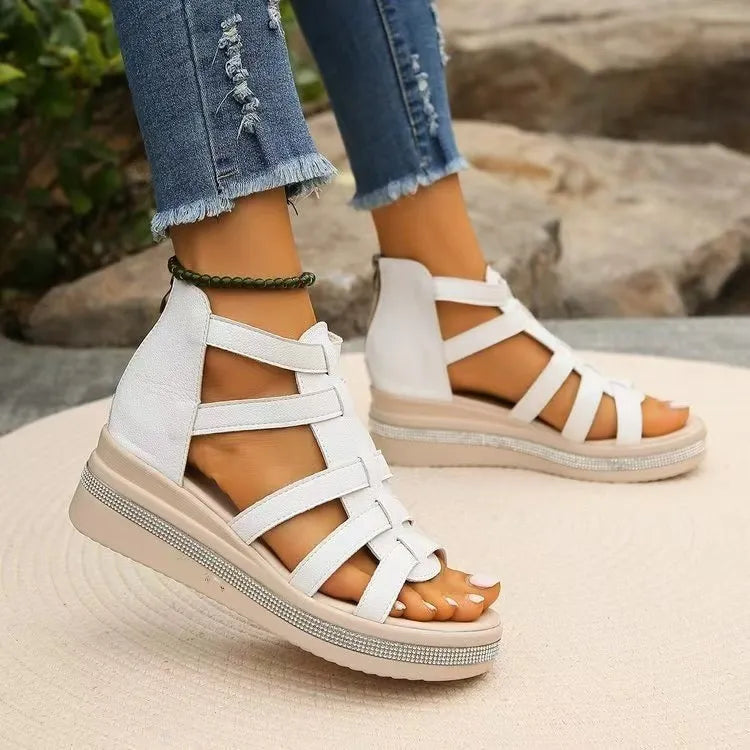 White gladiator wedge sandals with crystal trim and back zipper, styled with ripped jeans.