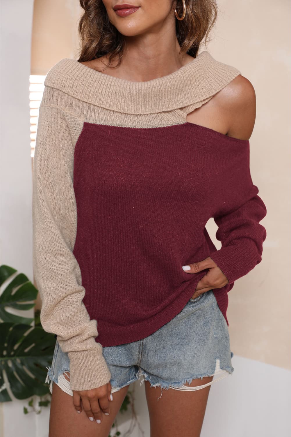 Asymmetric shoulder sweater in deep red and beige acrylic with a boat neck.