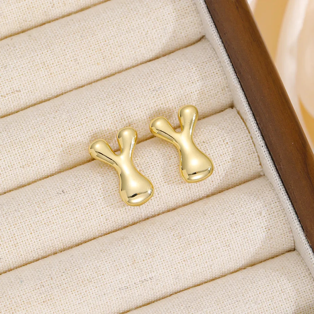 Gold sculpted stud earrings in the shape of the letter Y, made of copper.