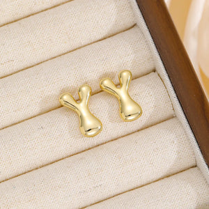 Gold sculpted stud earrings in the shape of the letter Y, made of copper.