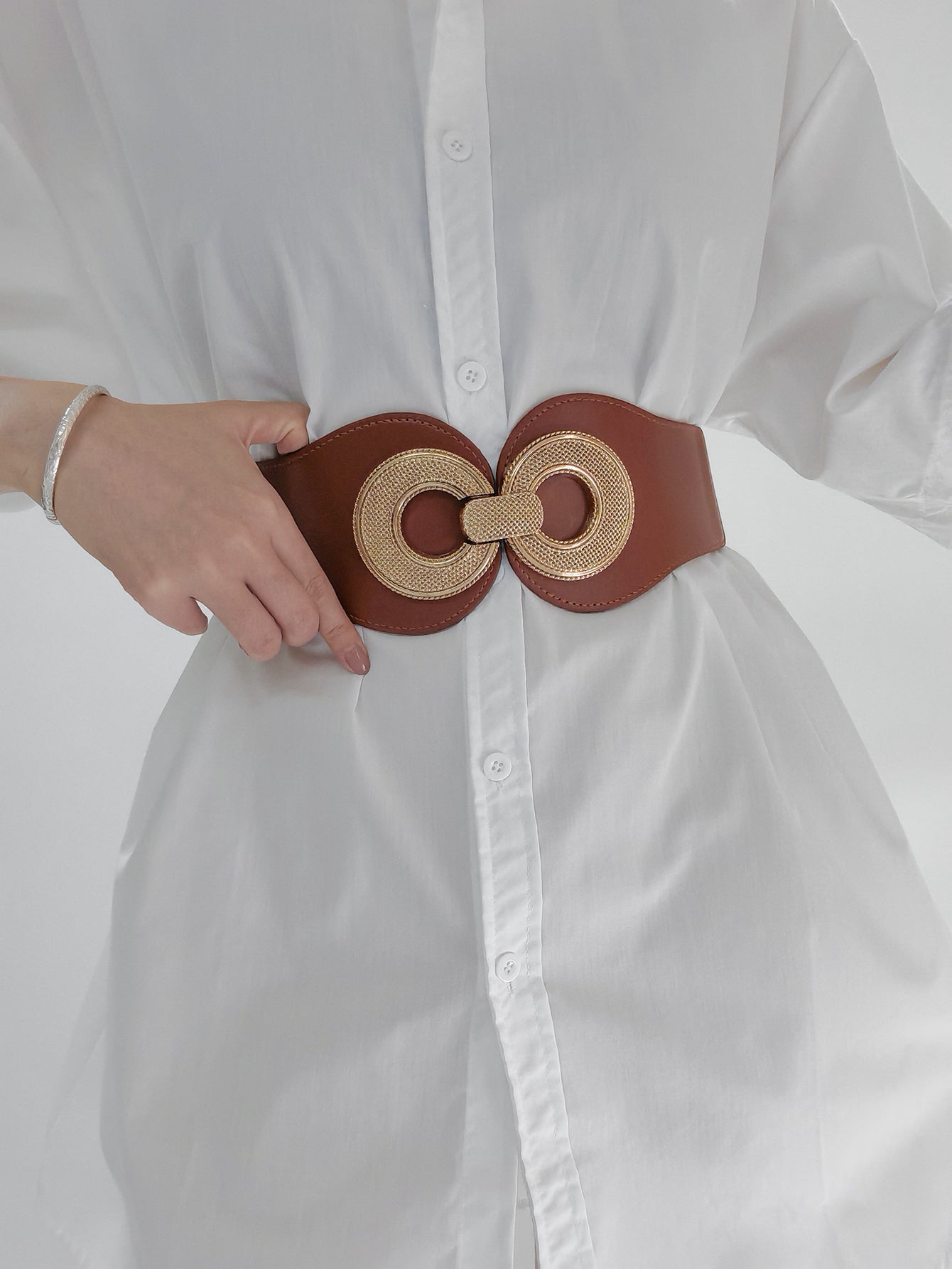 Caramel elastic waist belt with gold metalwork detail cinches a white shirt.
