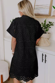 Black cotton dress with intricate eyelet details and short sleeves.