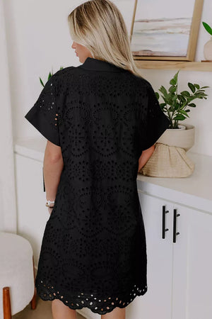 Black cotton dress with intricate eyelet details and short sleeves.