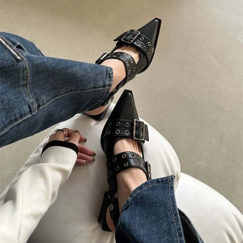 Black studded pointed-toe slingback flats with double buckle straps.