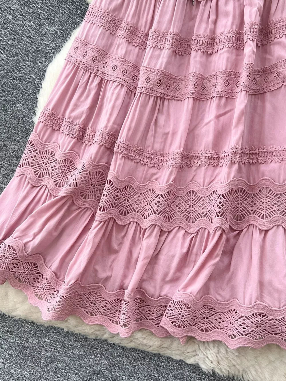 Pink tiered skirt with lace trim and drawstring detail.