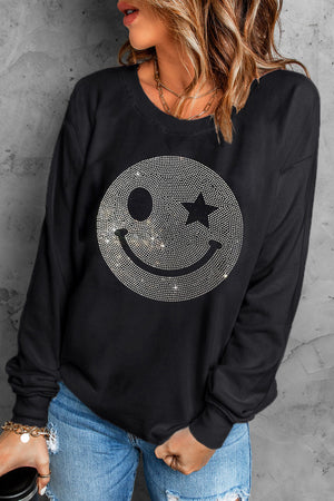 Black crewneck sweatshirt with a rhinestone wink-star smiley face graphic.