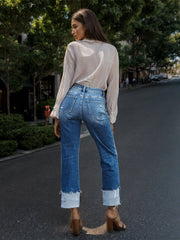 Medium wash cotton jeans with asymmetric waist cuff and distressed details.
