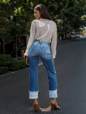 Medium wash cotton jeans with asymmetric waist cuff and distressed details.