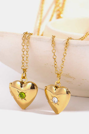 Gold heart locket necklace with green gemstone and diamond accent on chain