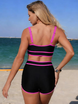 Black two-piece swimsuit with magenta contrast trim, featuring adjustable straps and high-waisted shorts.