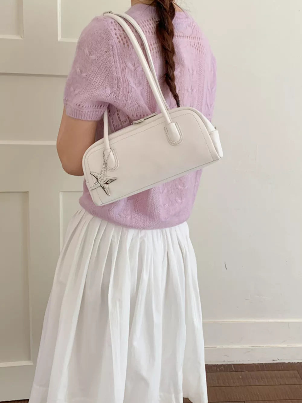 White shoulder bag with star charm and double straps.