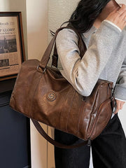 Brown pu leather duffel bag with zipper pocket and embossed logo detail.