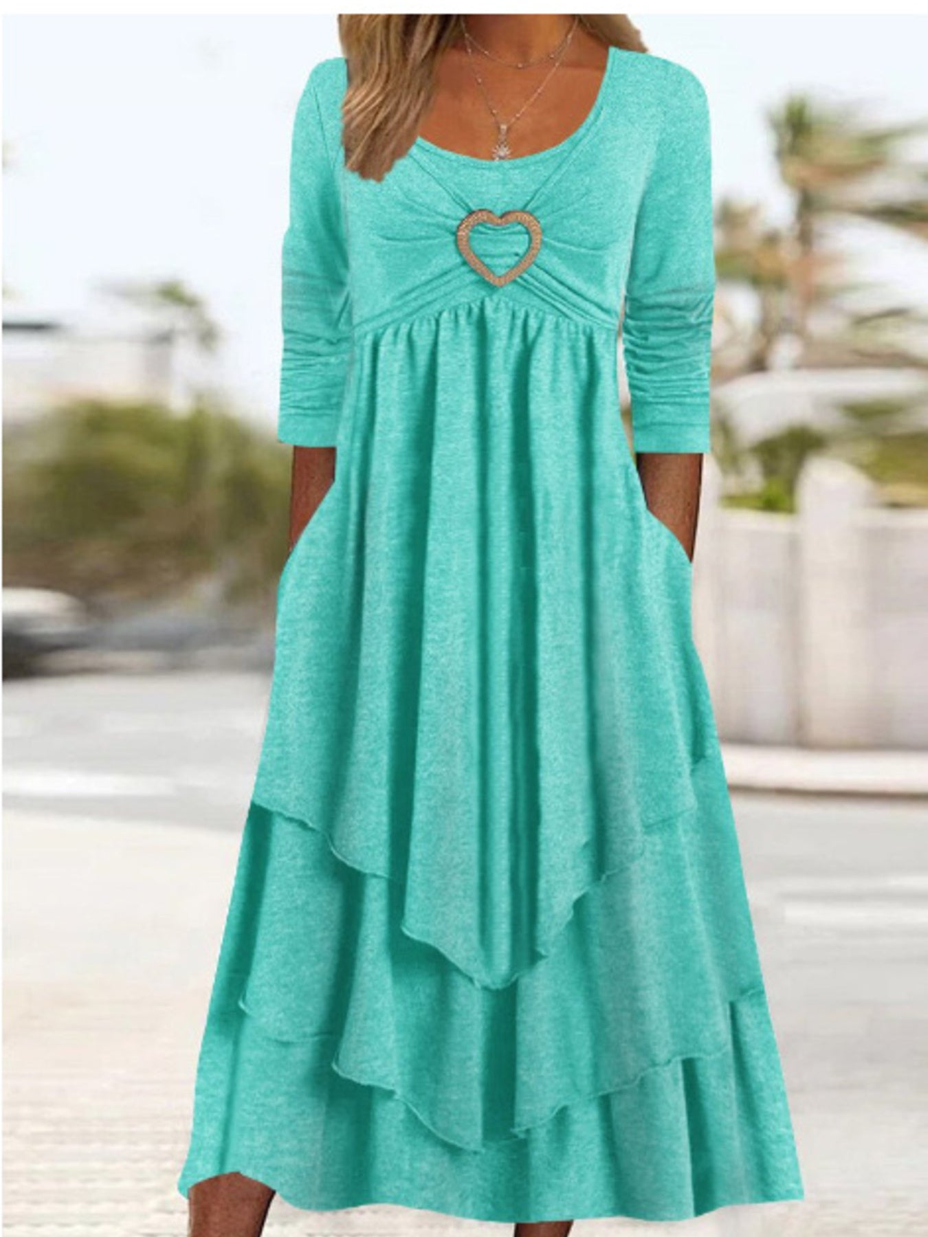 Turquoise midi dress with long sleeves, tiered skirt, and heart detail at neckline.