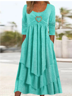 Turquoise midi dress with long sleeves, tiered skirt, and heart detail at neckline.