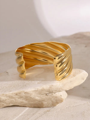 Gold cuff bracelet with sculpted wave texture and 18K gold plating.